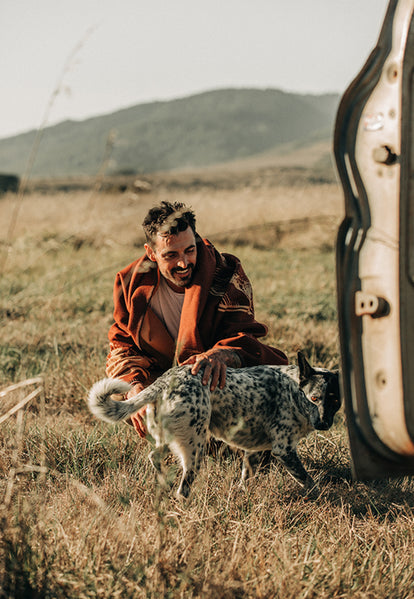 Man petting dog while our collaboration blanket with Pendleton is draped over him