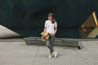 Our woman wearing that pants outside a brutalist building.