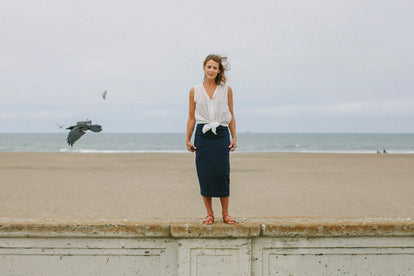 Modeling The Samantha, standing on a sea wall, gulls flying around in the background.