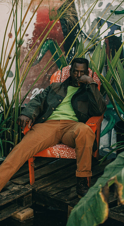 Ron Finley sitting in his garden while wearing
  The Carpenter Pant in Cedar Boss Duck and The Heavy Bag Tee in Chlorophyll.