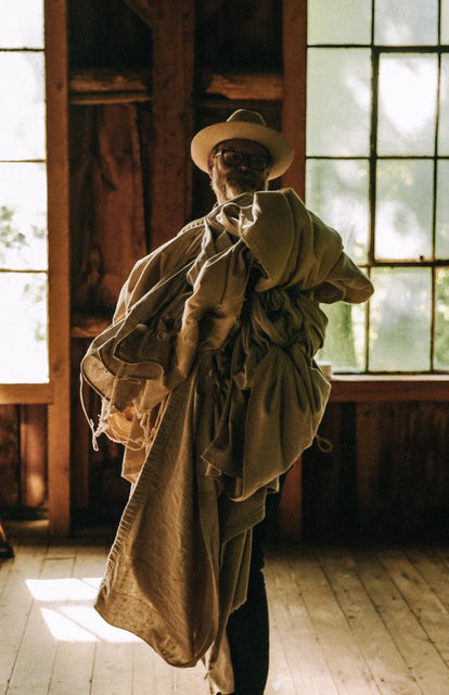 Mark Holthusen holding old curtains in a barn at Springhill Farm