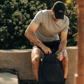 fit model zipping up backpack wearing The Merino Base Layer Tee in Sharkskin , Knits by Taylor Stitch