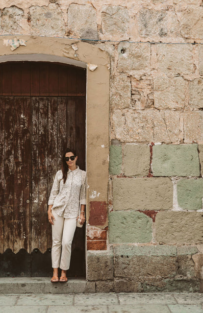 A wona leaning against a large wooden door in a an oversized stone doorway.