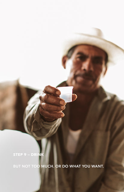 Step 9: Drink - a man holding up a small plastic shot glass to the camera.