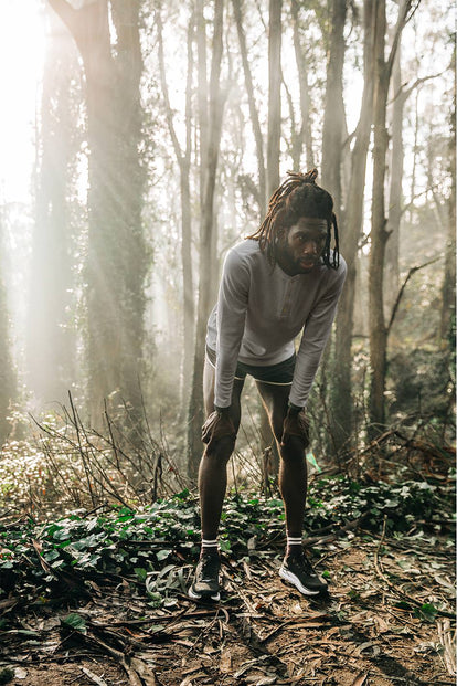 Our guy with his hands on knees on a forested trail.