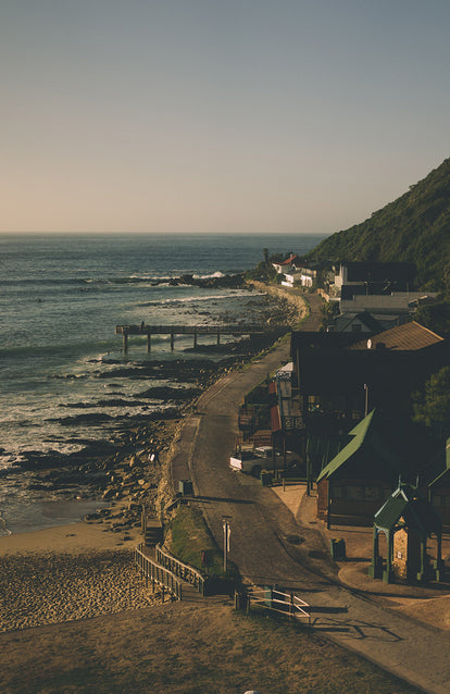 A road hugging the shoreline of a rocky coastline with low key housing.