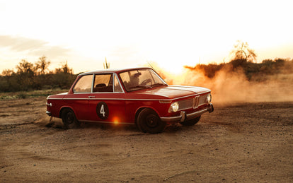 Nico driving his BMW hard through the desert, kicking up dust.