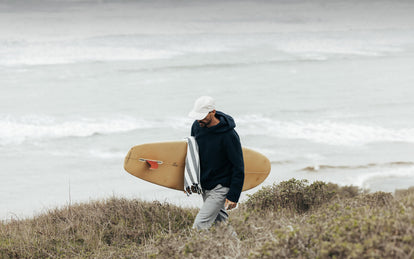 Our man walking back up the bluffs, carrying his surfboard