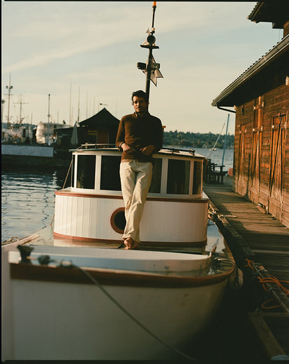 Model on a boat, wearing The Lodge Sweater in Timber Donegal