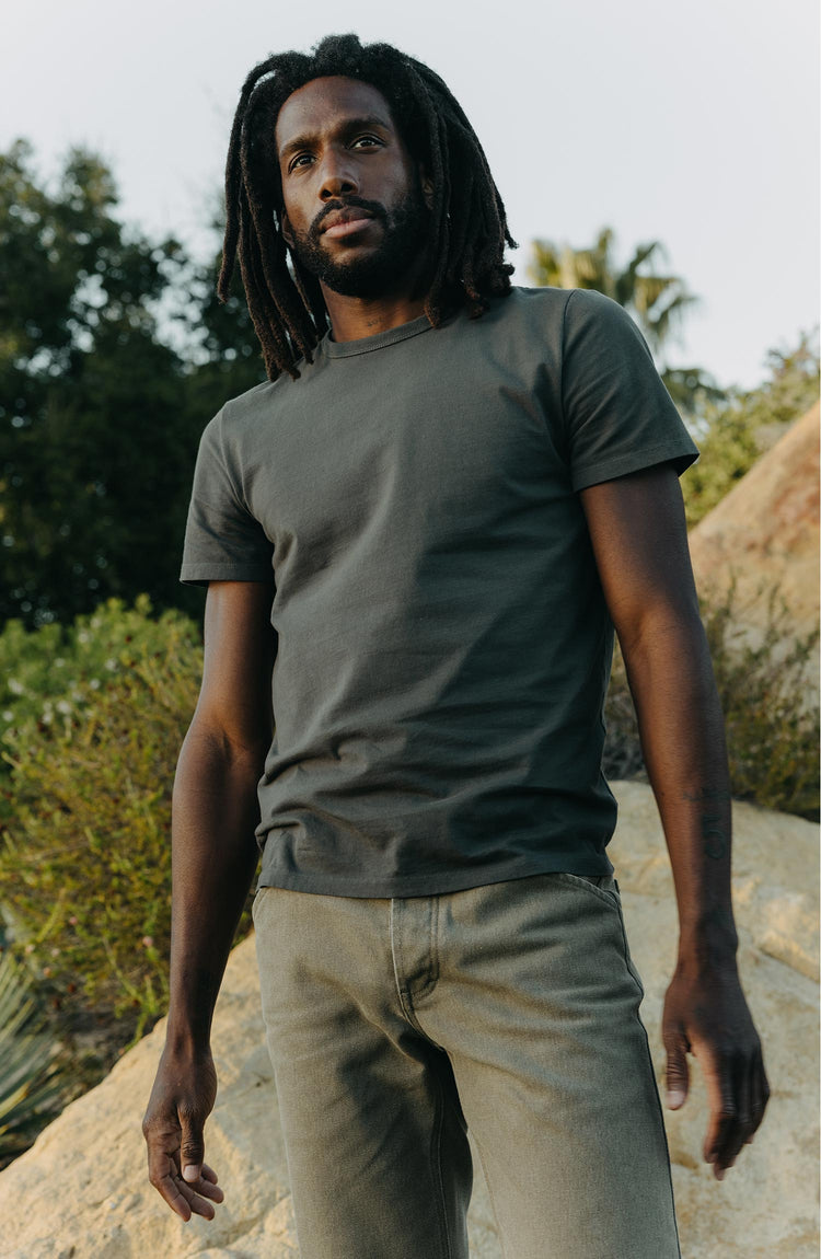 fit model posing on a rock wearing The Organic Cotton Tee in Faded Black