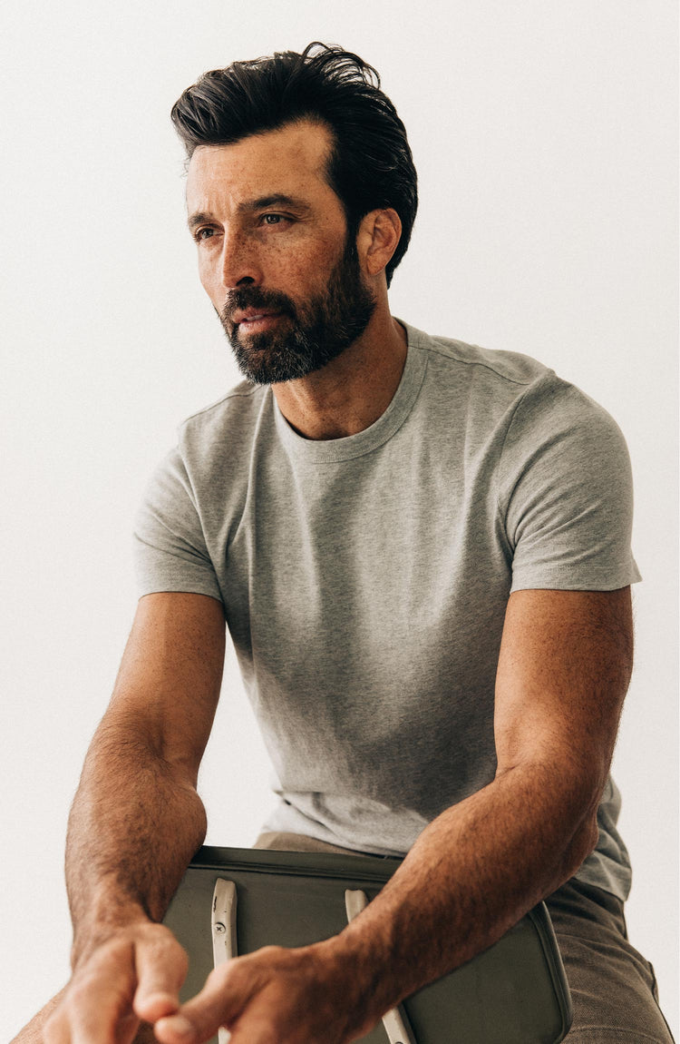 fit model sitting on a chair wearing The Organic Cotton Tee in Heather Grey