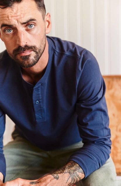 fit model leaning on his legs wearing The Organic Cotton Henley in Navy