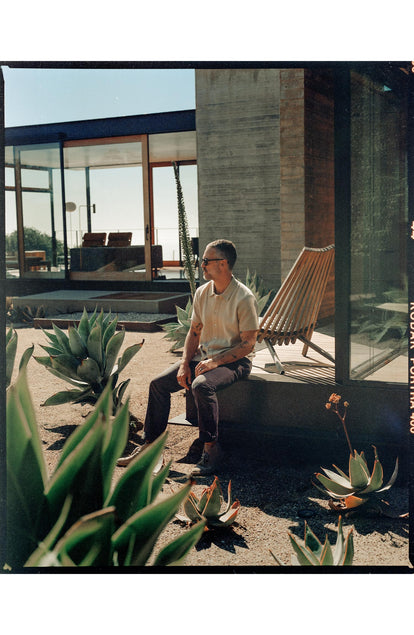 fit model sitting wearing The Button Down Polo in Faded Khaki Seed Stitch