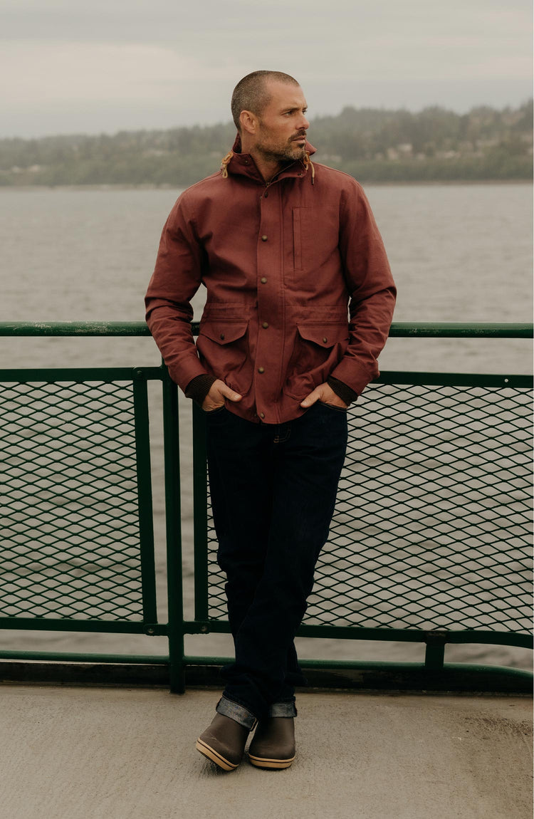 fit model leaning against a railing wearing The Explorer Jacket in Red Wine Dry Wax