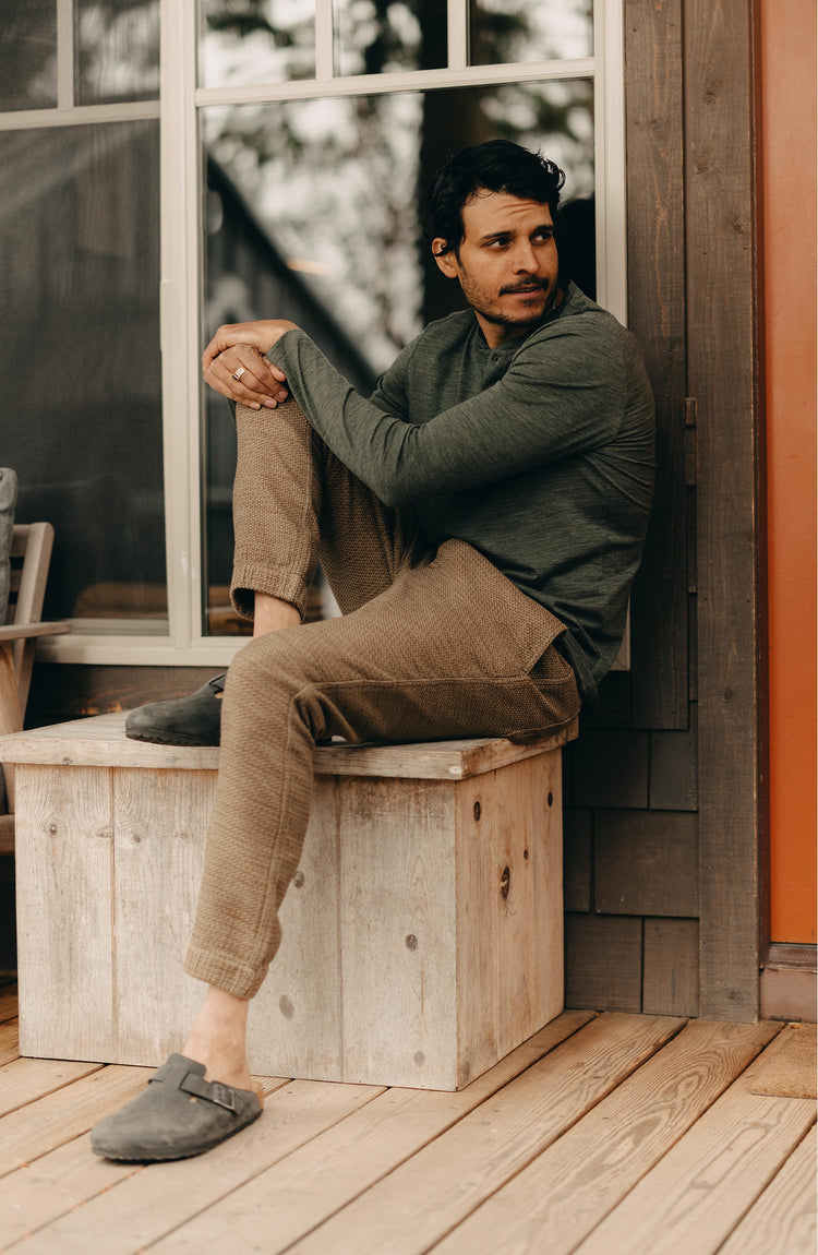 fit model sitting wearing The Merino Henley in Heather Army