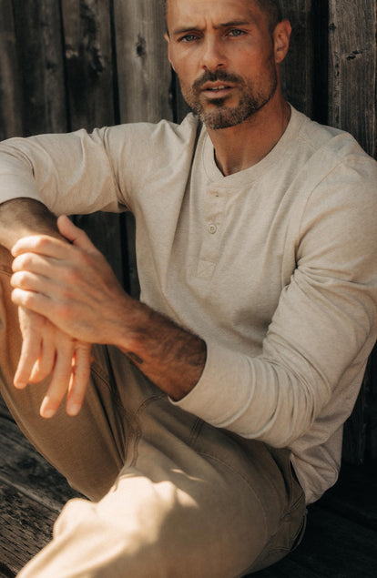 fit model sitting wearing The Organic Cotton Henley in Heather Oat