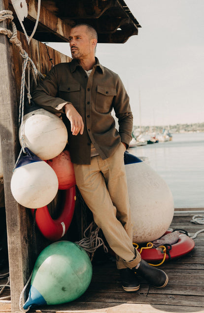 fit model leaning against the wall wearing The Surplus Pant in Khaki Reverse Sateen