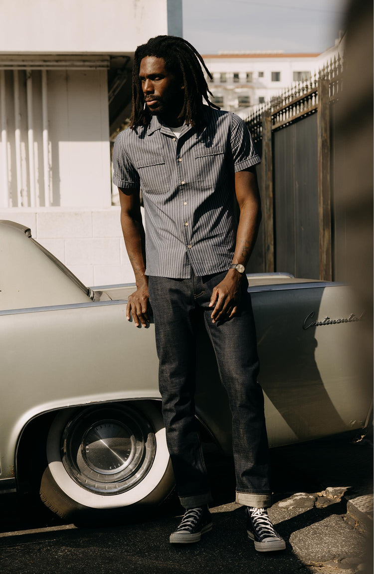 fit model leaning on a car wearing The Tulum Shirt in Midnight Stripe