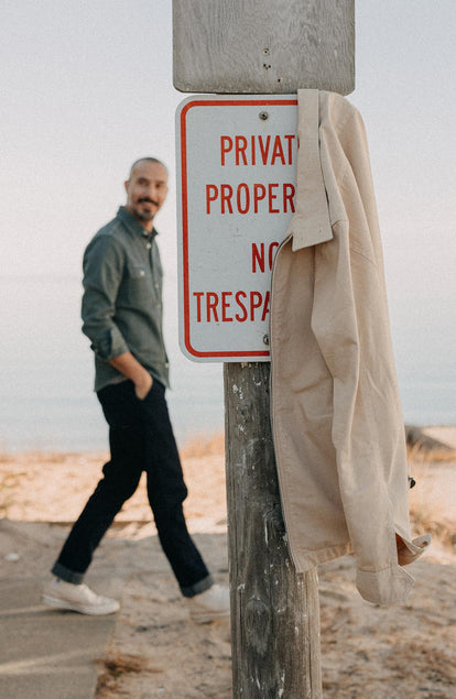 fit model walking next to The Flint Jacket in Light Khaki Broken Twill hanging