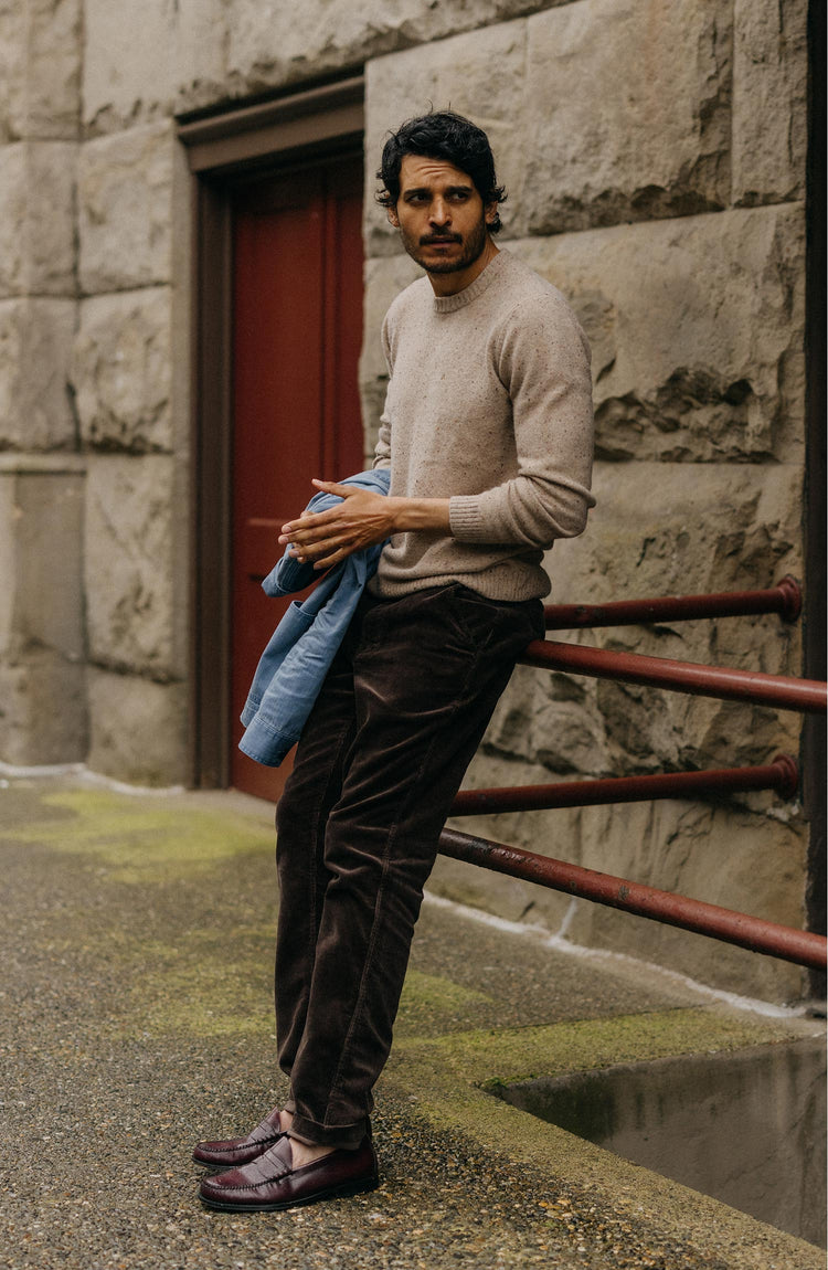 fit model leaning against the railing wearing The Lodge Sweater in Sand Donegal