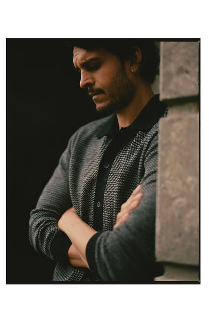 fit model leaning against the wall wearing The Nichols Polo in Black Birdseye Merino