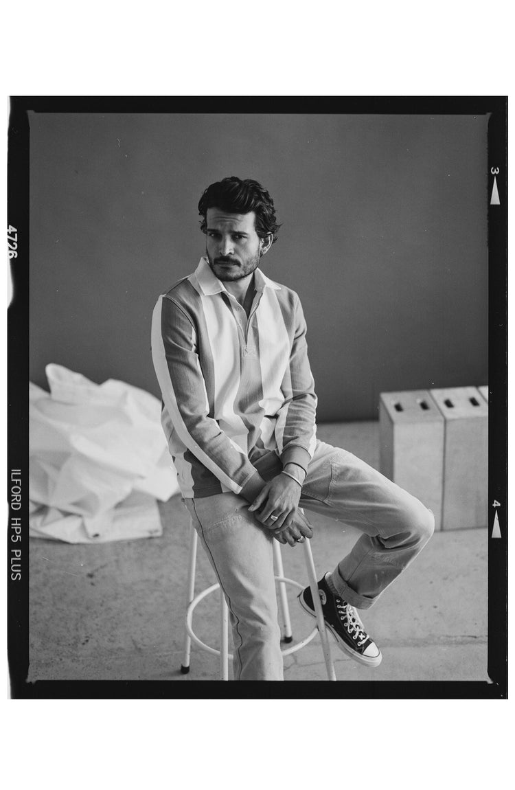 fit model sitting on a stool wearing The Rugby Shirt in Deep Sea Stripe