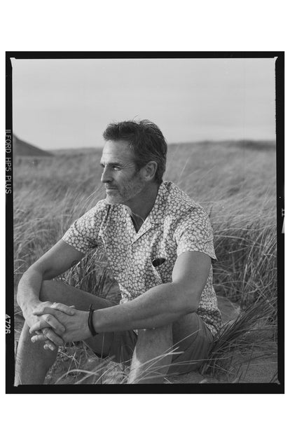 fit model sitting in the grass wearing The Short Sleeve Hawthorne in Fig Floral