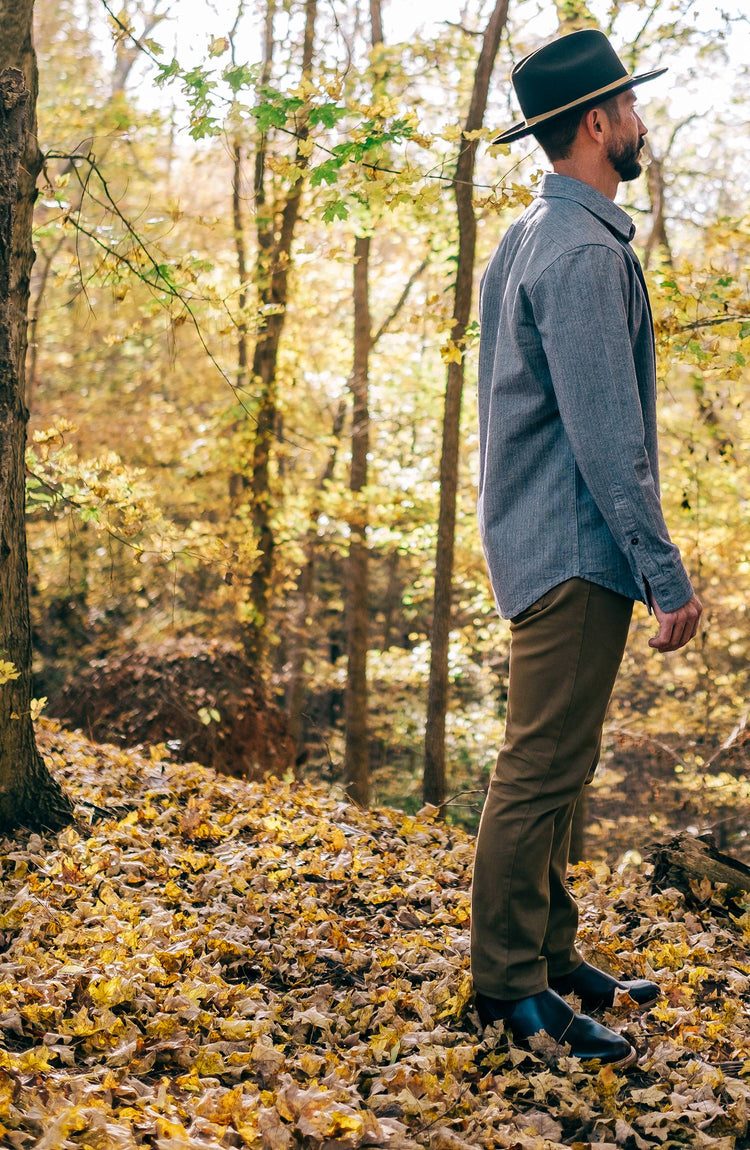 Head shot of our guy wearing a Stetson hat, looking off camera with woodland in the background.