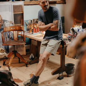 fit model sitting on a work desk wearing The Apres Trail Short in Light Sage Slub, Bottoms by Taylor Stitch