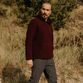 fit model walking in a field in The Nomad Hoodie in Burgundy Sherpa, Outerwear by Taylor Stitch