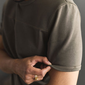 fit model adjusting the sleeves on The Rugby Tee in Smoked Olive, Knits by Taylor Stitch