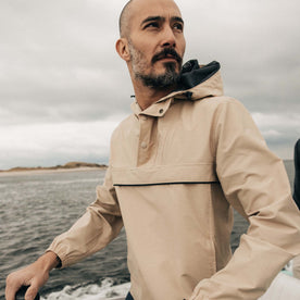 fit model posing on a boat wearing The Chapman Anorak in Light Khaki, Outerwear by Taylor Stitch