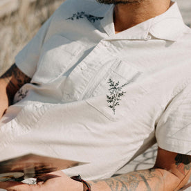 fit model lying on the beach wearing The Conrad Shirt in Seaside Embroidery, Wovens by Taylor Stitch