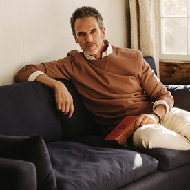 fit model on a couch in The Cotton Hemp Crew in Faded Brick, Knits by Taylor Stitch