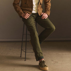 fit model sitting on a stool wearing The Democratic Jean in Olive Nihon Menpu Selvage, Bottoms by Taylor Stitch