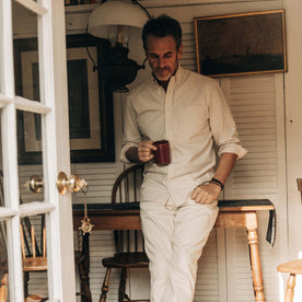 fit model leaning against a wooden desk in The Jack in Sunburn Stripe Oxford, Wovens by Taylor Stitch