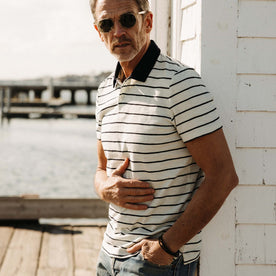 fit model leaning against the wall wearing The Organic Cotton Polo in Bleached Natural Stripe, Knits by Taylor Stitch