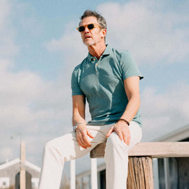 fit model sitting on a bench wearing The Organic Cotton Polo in Washed Indigo, Knits by Taylor Stitch