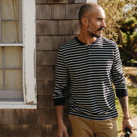 fit model leaning on a house wearing The Organic Cotton Henley in Rinsed Indigo Stripe, Knits by Taylor Stitch