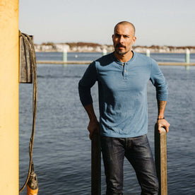 fit model standing on a dock wearing The Organic Cotton Henley in Washed Indigo, Knits by Taylor Stitch