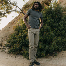 fit model posing next to a bush wearing The Organic Cotton Tee in Faded Black, Knits by Taylor Stitch