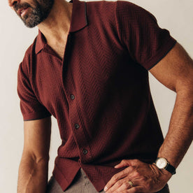 fit model sitting in The Button Down Polo in Dried Cherry Herringbone, Knits by Taylor Stitch