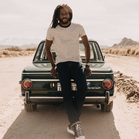 fit model leaning against a car wearing The Cotton Hemp Tee in Black Coffee Stripe, Knits by Taylor Stitch