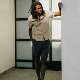 fit model leaning against the wall wearing The Palmer Shirt in Cilantro, Wovens by Taylor Stitch