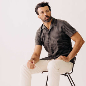 fit model sitting wearing The Short Sleeve Davis Shirt in Kelp Stripe, Wovens by Taylor Stitch