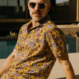 fit model sitting wearing The Short Sleeve Davis Shirt in Tarnished Gold Print, Wovens by Taylor Stitch