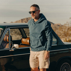 fit model posing next to a car wearing The Apres Hoodie in Washed Indigo Terry, Knits by Taylor Stitch