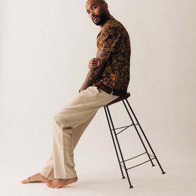 fit model sitting on a stool wearing The Breakwater Pant in Natural Herringbone, Bottoms by Taylor Stitch