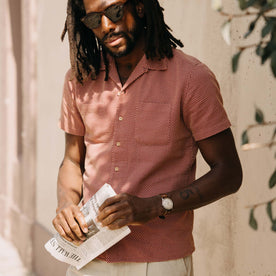 fit model holding a newspaper wearing The Conrad Shirt in Fired Brick Dobby, Wovens by Taylor Stitch