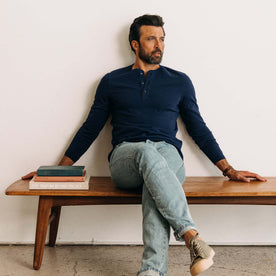 fit model sitting on a bench wearing The Heavy Bag Henley in Navy, Knits by Taylor Stitch